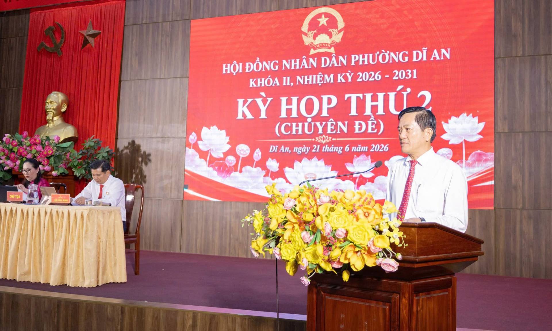Có thể là hình ảnh về cái bục và văn bản cho biết 'HỘI ĐỒNG NHÂN DÂN PHƯỜNG DĨ AN KHÓA II, NHIỆM KỲ 2026 2031 KY HOP THỨ (CHÜYÊN ĐỀ) ー Di An, ngày 21 tháng 6 năm 2026 ആർத'